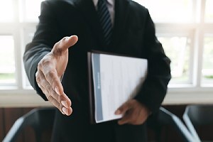 A job seeker extending his hand. Outsourcing to a third-party cybersecurity consulting firm is a cost-effective option
