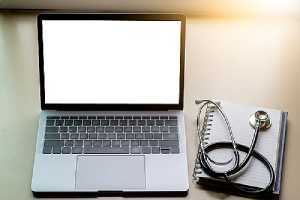 A laptop, medical stethoscope and notebook on office desk. Telehealth technology also comes with certain drawbacks