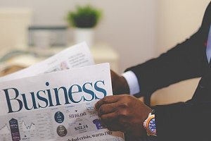 Businessman opening a newspaper. A closed market transaction is the opposite of an open market transaction