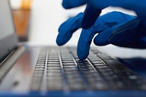 Hand in gloves typing on keyboard. Cybersecurity Risks concept