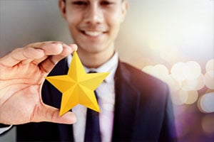 Happy Businessman in black suit Smiling and Showing a Golden Star in Hand