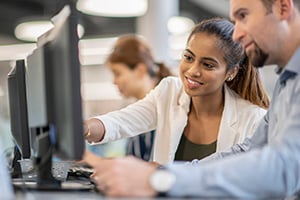 Two colleagues looking at computer and speaking