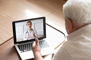 close up older man talking with doctor by video call