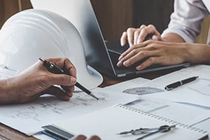 Construction workers at desk working on laptop