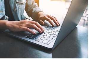 Hands typing at a laptop
