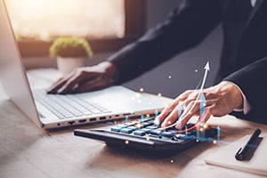 Man at desk on calculator and laptop