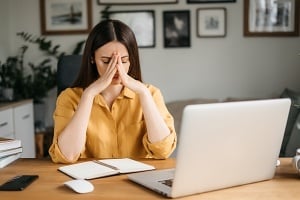 stressed college student hunched over their desk
