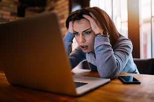 Woman reacting negatively to computer hacking 