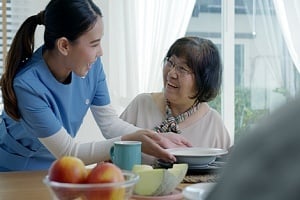 young women helping two senior living residents with breakfast
